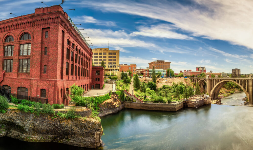 Washington Water Power building and the Monroe Street Bridge in Spokane Wide-angle view of Washington Water Power building and the Monroe Street Bridge along the Spokane river, in Spokane, Washington.